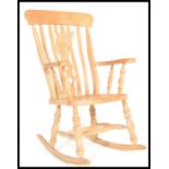 An antique style beech wood Windsor style lathe back rocking chair. Raised on turned legs on