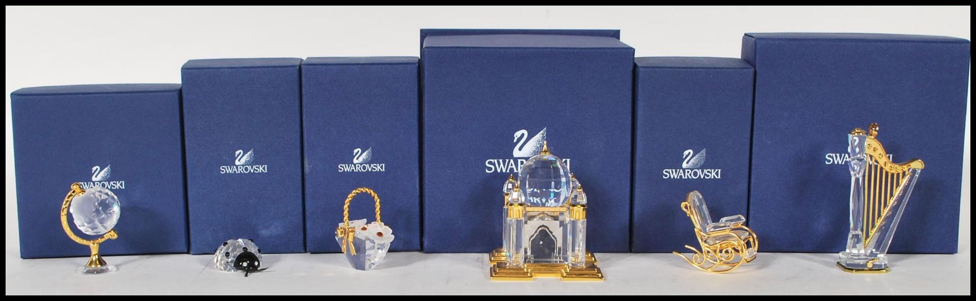 Swarovski - A collection of cut glass crystal figurines to include a harp, a globe, a rocking chair,
