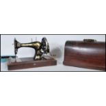 An early 20th Century oak cased manual Singer sewing machine, black body with gilt detailing