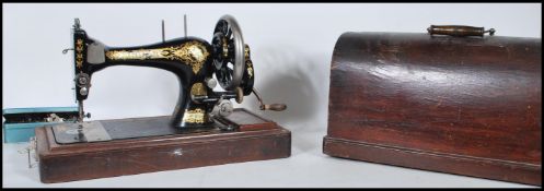 An early 20th Century oak cased manual Singer sewing machine, black body with gilt detailing