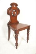 A 19th Century Victorian mahogany hall chair raised on turned legs with C scroll back and armorial