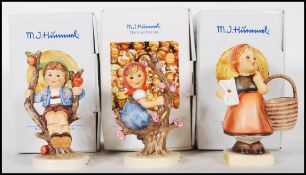 A group of three German Goebel Hummel figurines in boxes to include Herbet Apple tree boy,