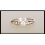 A stamped 375 9ct white gold ring set with a central round cut stone with accent stones to the
