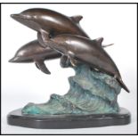 A 20th Century cast brass figurine / ornament in the form of three dolphins riding the crest of a