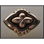 A 19th Century Victorian gold tone mourning brooch of quatrefoil form having a glazed panel to the