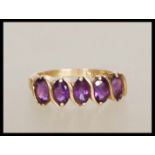 A stamped 10k 9ct gold ring set with five oval cut purple stones. Weight 1.8g. Size M.