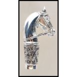 A silver walking stick handle in the form of a horse having floral decorated collar with a central