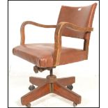 A 1930's Art Deco oak framed swivel desk chair having shaped arm rests being raised on a central