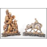 Two Chinese carved soapstone figural groups, the first of a man riding on the back of a water
