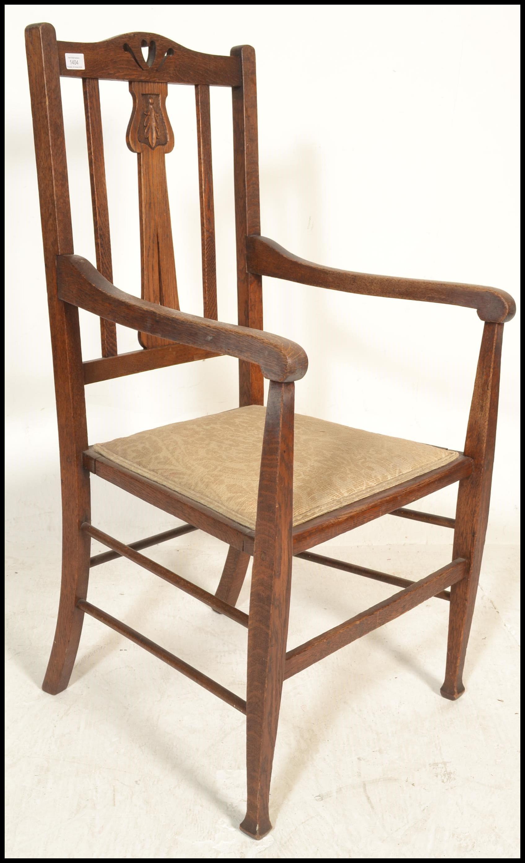 A late 19th / early 20th Century Art Nouveau oak elbow chair, pierced backrest over carved splatback