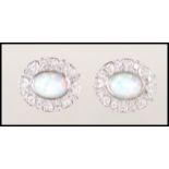 A pair of silver oval flower shaped earrings set with a central opal surrounded by a cluster of Cz'