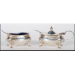 A pair of silver hallmarked table condiments complete with blue glass liners and condiment spoons.