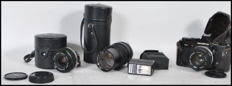 A vintage Olympus OM-2N film camera with a 1:1.8 f=50mm lens along with two more lenses, an