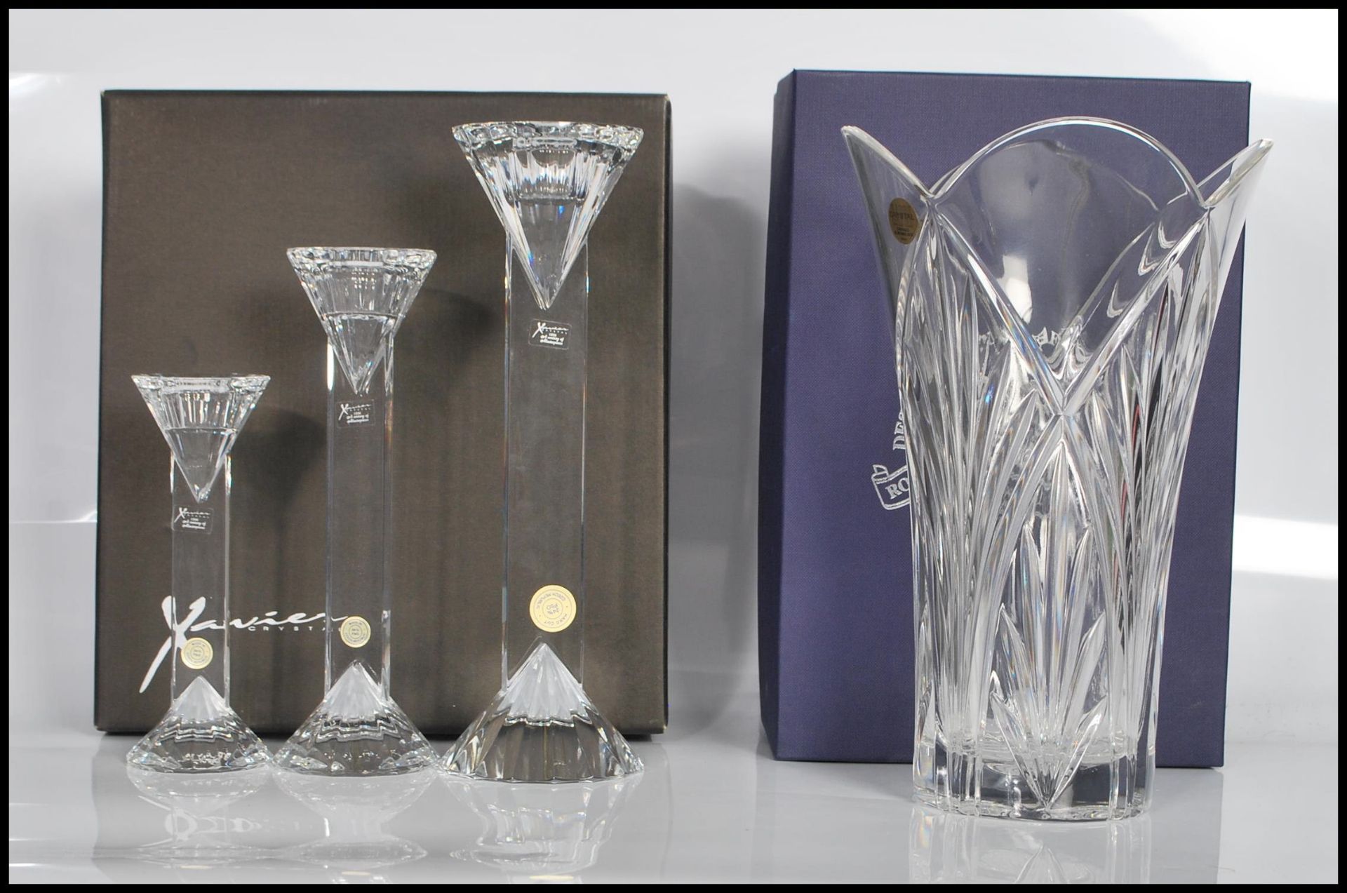 A boxed set of three Xavier Crystal candlesticks of graduating form having shaped rounded tops and