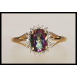An English hallmarked 9ct gold ring set with an oval cut mystic topaz having a halo of white