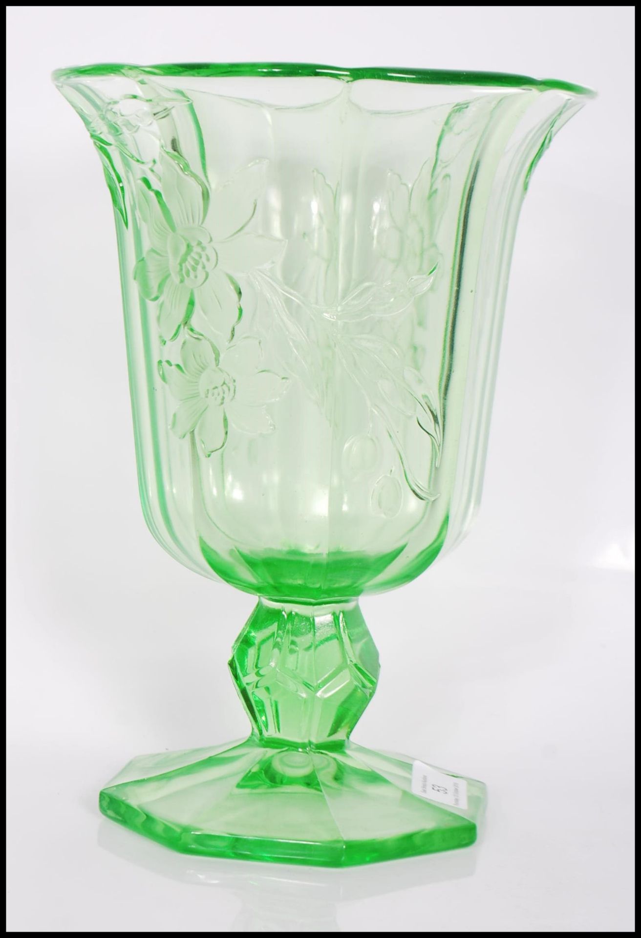 An early 20th Century Art Deco pressed green glass footed vase of octagonal form having raised