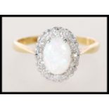 A stamped 18ct gold ladies ring set with an oval opal cabochon having a halo of white stones. Weight