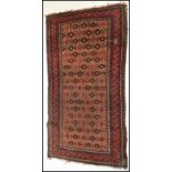 A 20th Century woolen hand knotted carpet floor rug on red ground, central geometric panel