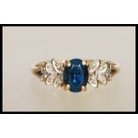 An English hallmarked 9ct gold dress ring set with an oval cut blue stone with graduating foliate