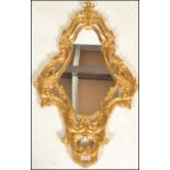 A 20th Century gilt rococo style wall mirror having a symmetrical reeded gilt frame with scrolled