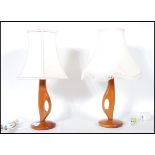 A pair of mid 20th century retro teak table lamps of angular sculptured form raised on circular