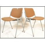 A pair of mid century retro office chairs having fabric upholstered seat frames being raised on