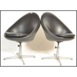 A pair of contemporary retro style swivel tub chairs, upholstered in a black leatherette material
