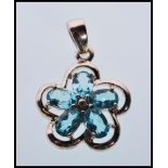 A hallmarked 9ct white gold pendant in the form of a flower set with five oval faceted cut blue