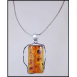A silver stamped 925 necklace and pendant, the pendent having a Baltic Amber lozenge central panel