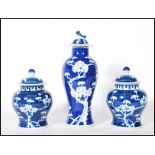 A harlequin garniture of three Chinese blue and white lidded jars to include a pair of ginger jars
