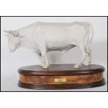 Alessandro Maggioni. A good Italian 1976 porcelain figurine of a bull raised on a walnut plinth with