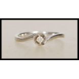 A stamped 375 white gold solitaire ring of cross over design set with a round cut white stone.