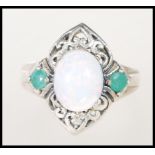 A stamped 925 silver ladies dress ring set with an opal flanked by two green stones on a
