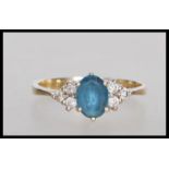 An English hallmarked 9ct gold ring set with an oval cut blue stone flanked with six round cut white