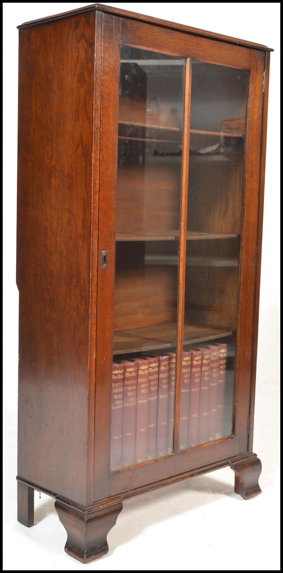 A mid century Queen Anne solid oak bookcase cabinet being raised on bracket feet with full length