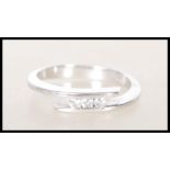 A stamped 750 18ct white gold ring of wrap around design set with three round cut diamonds. Diamonds