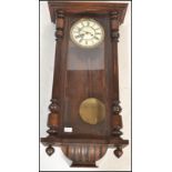 A 19th Century Vienna wall clock set within a mahogany case with glazed panel door flanked by turned