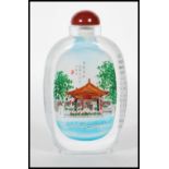A Chinese glass scent bottle having interior painted decoration depicting a river scene with outdoor
