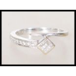 A stamped 750 18ct white gold tapering wrap around ring set with round and square cut diamond accent