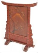 An early 20th Century Japanese red and black lacquer fire screen having the central front panel