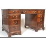 An antique style mahogany and tooled leather twin pedestal writing desk. Raised on bracket feet with