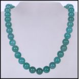 A 20th Century Chinese beaded and knotted green jade necklace, with silver white metal lobster