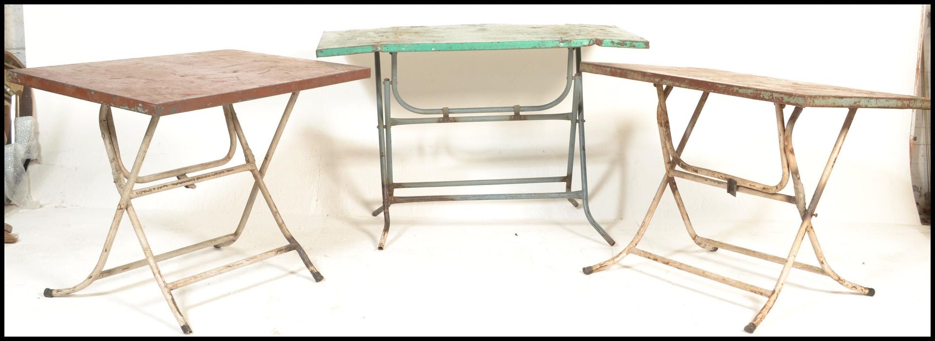 A set of retro 20th century metal folding cafe tables. Each with folding metal leg bases having