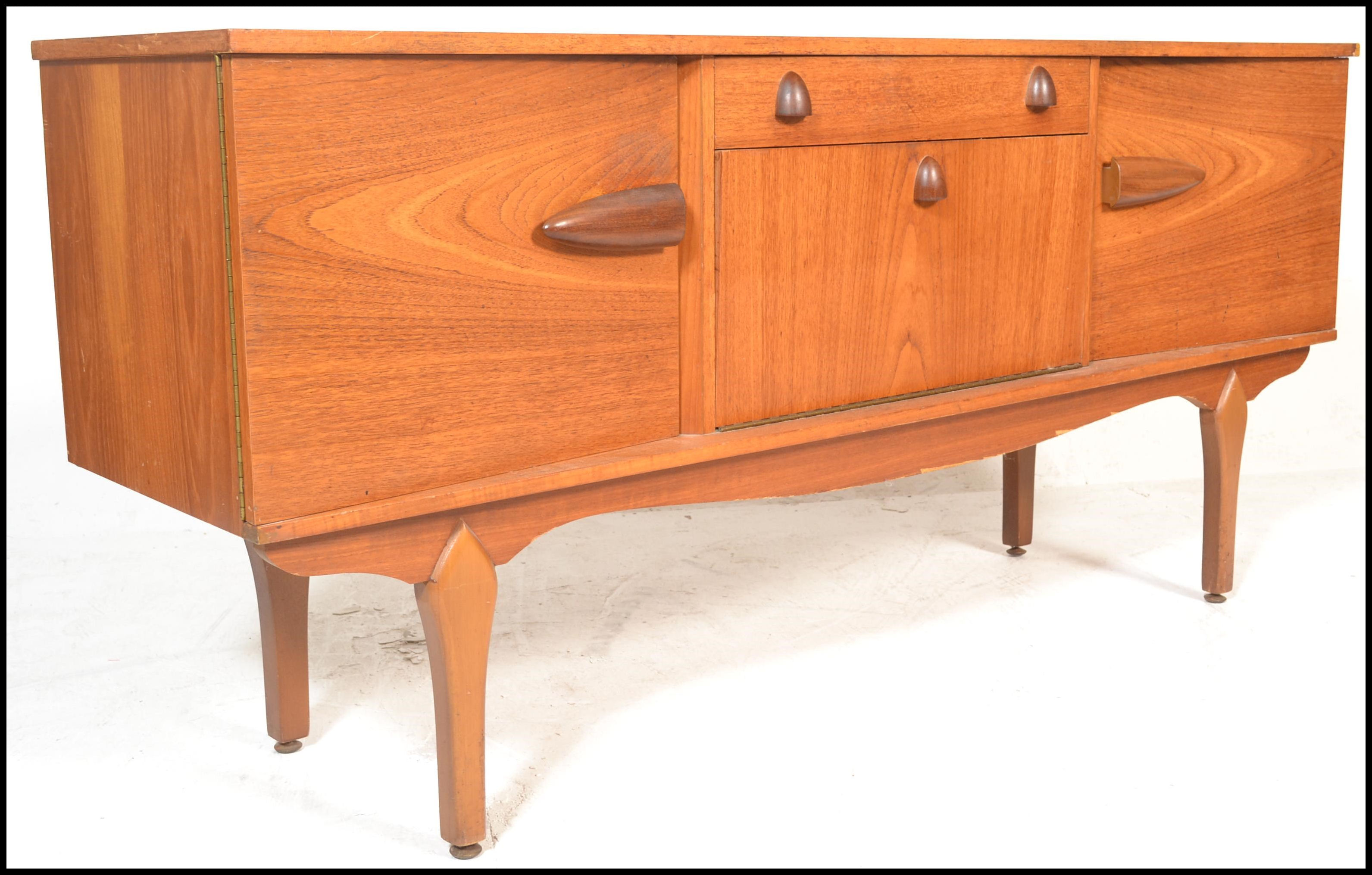 A vintage mid 20th century teak wood sideboard having a central drop down bar compartment with
