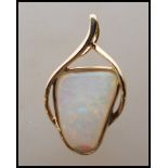 A stamped 14ct gold pendant having a crossover design set with an opal panel. Weight 1.5g.