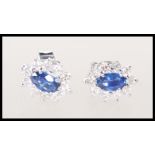 A pair of 18ct white gold earrings set with central oval faceted cut sapphire with a halo of
