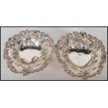 A pair of early 20th century silver pin dishes of rococo form with pierced basked design.