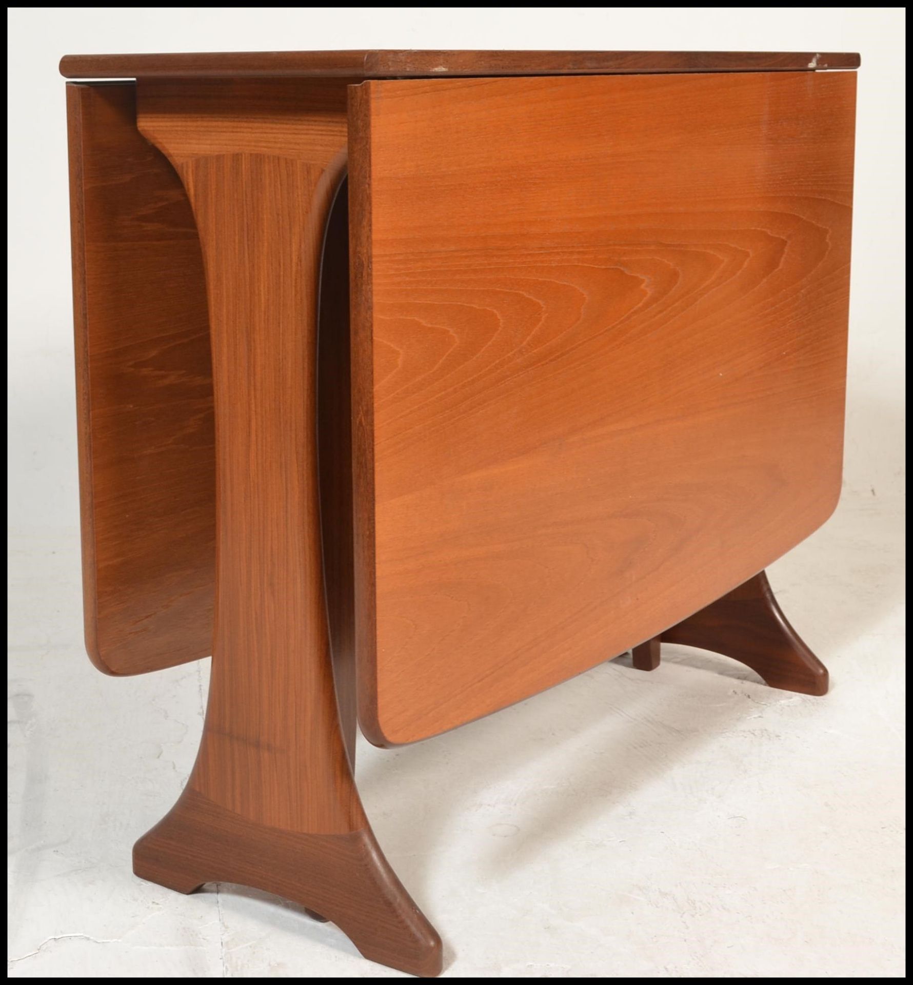 A 1970's teak wood Danish influenced G-Plan drop leaf dining table raised on shaped supports with