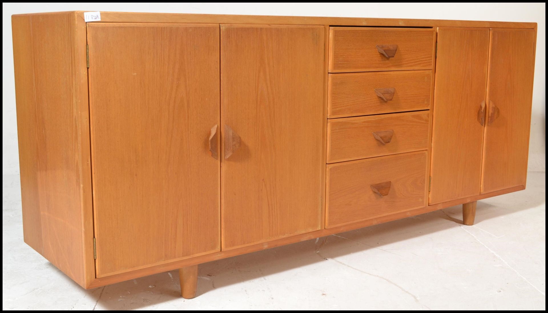 A mid century Ercol manner oak sideboard credenza being raised on stub turned legs with a wide and
