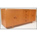 A mid century Ercol manner oak sideboard credenza being raised on stub turned legs with a wide and